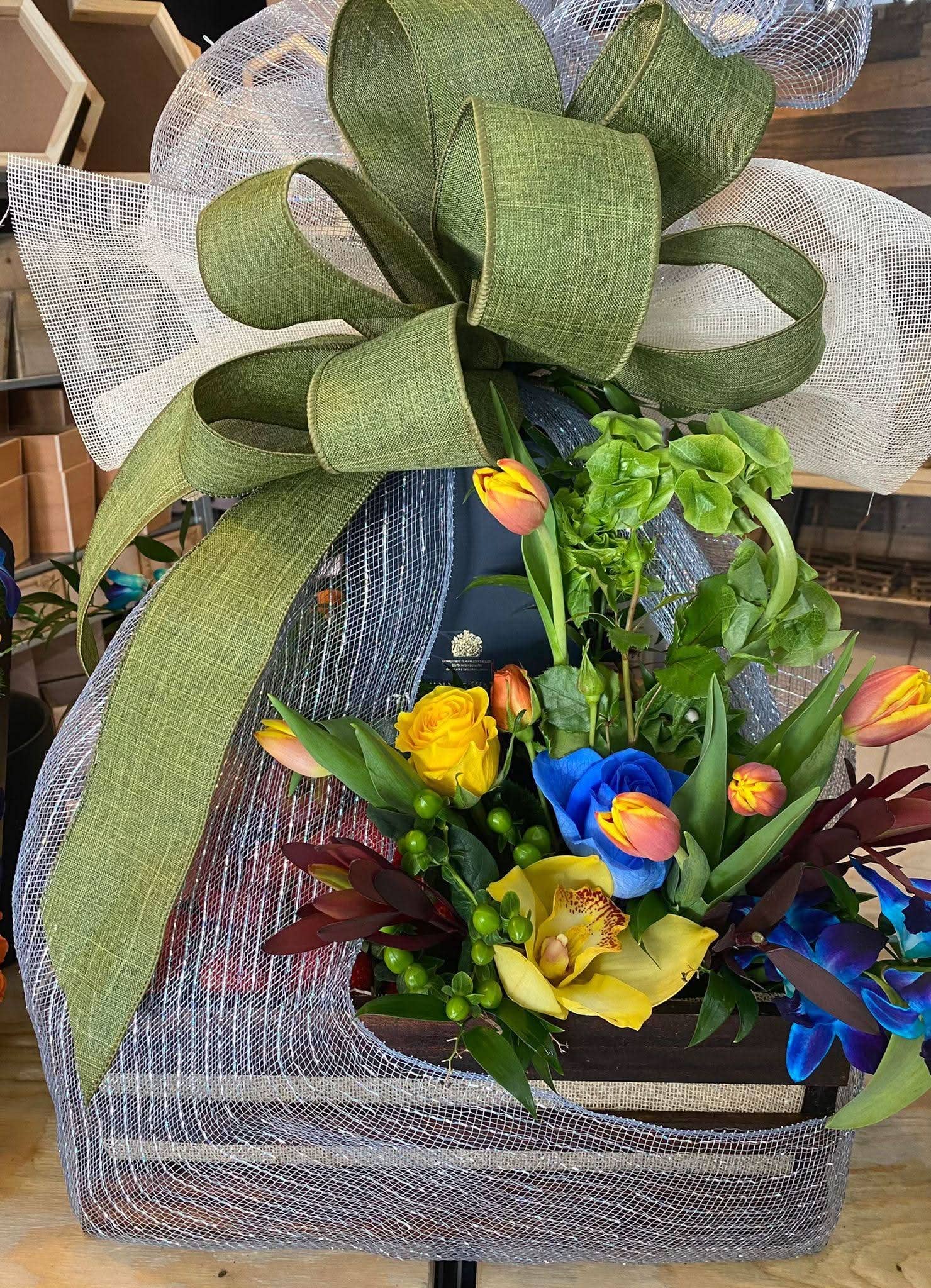 Arreglo floral con lazo verde, flores frescas amarillas, azules y tulipanes